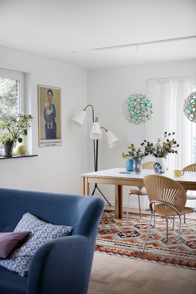 Immagine di una sala da pranzo aperta verso il soggiorno scandinava con pareti bianche, parquet chiaro e pavimento beige