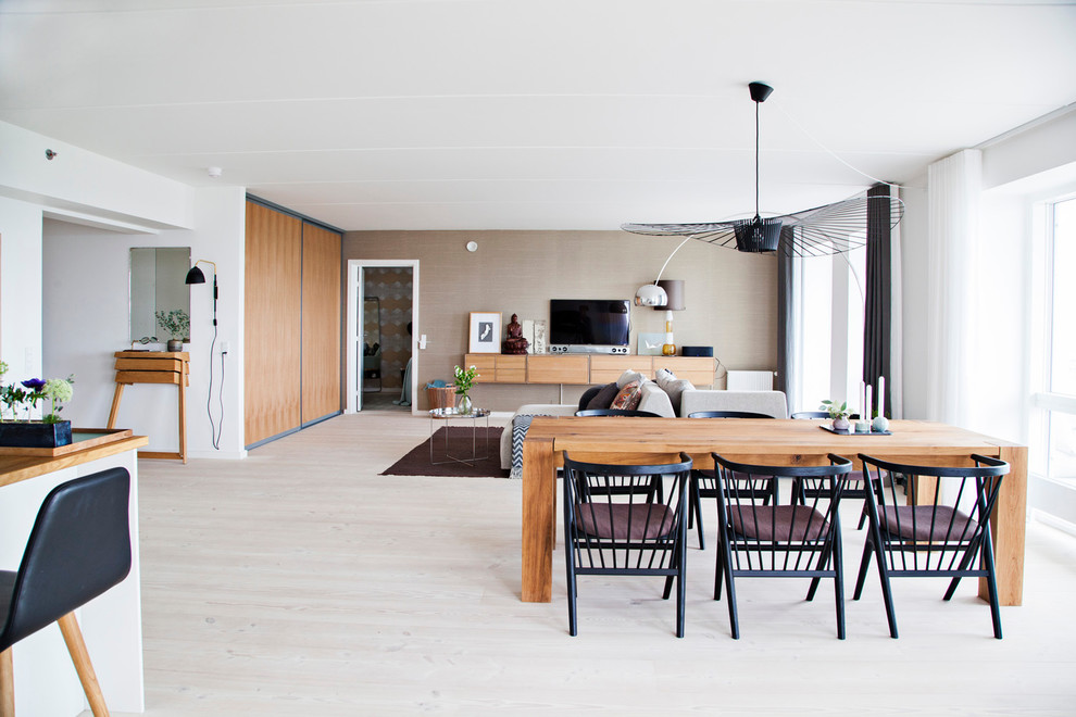 Foto di una sala da pranzo aperta verso il soggiorno scandinava con pareti bianche, parquet chiaro e nessun camino