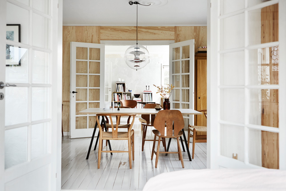 На фото: отдельная столовая в скандинавском стиле с коричневыми стенами, деревянным полом и белым полом