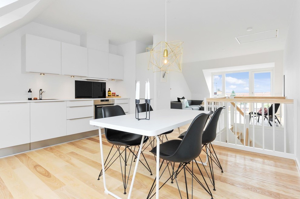 Immagine di una sala da pranzo aperta verso la cucina scandinava di medie dimensioni con pareti bianche, parquet chiaro e nessun camino