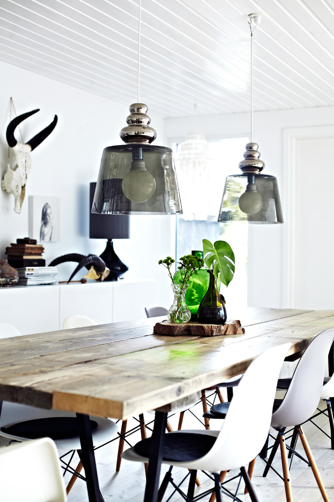 This is an example of a scandinavian dining room in Copenhagen with white walls, light hardwood flooring, beige floors and feature lighting.