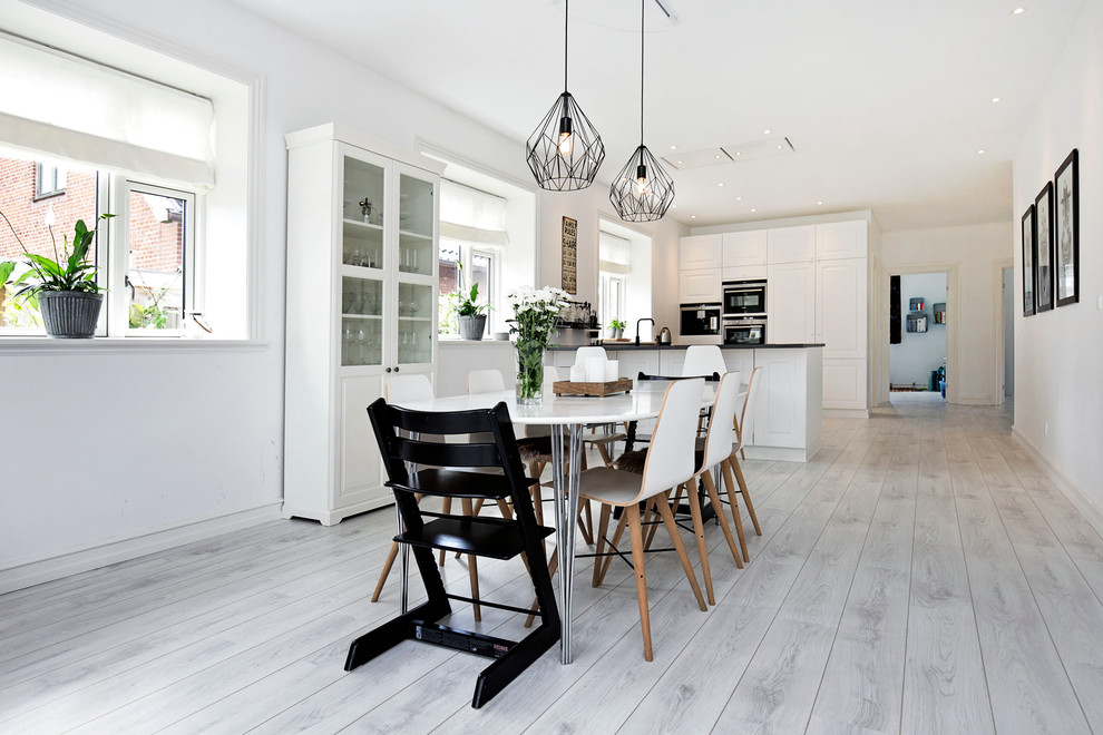 Foto de comedor de cocina escandinavo grande sin chimenea con paredes blancas y suelo de madera clara