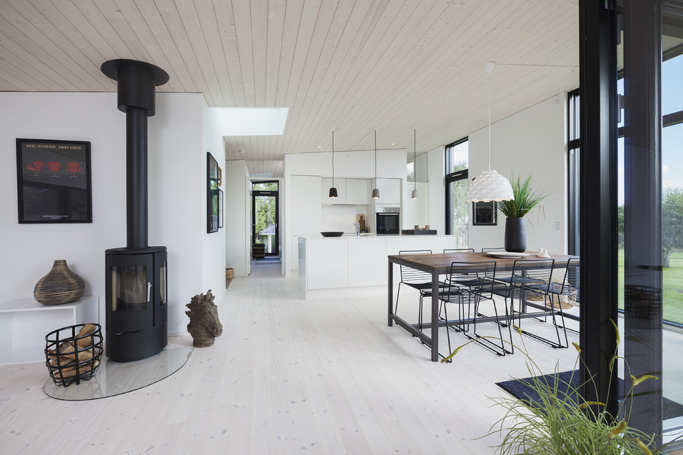 Inspiration för en skandinavisk matplats, med vita väggar, en öppen vedspis, en spiselkrans i metall, vitt golv och ljust trägolv