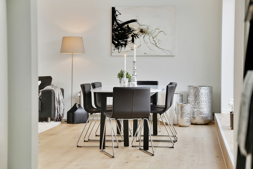 Contemporary dining room in Copenhagen with white walls, light hardwood flooring and beige floors.
