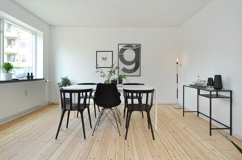 Immagine di una sala da pranzo nordica chiusa e di medie dimensioni con pareti bianche, parquet chiaro e pavimento beige