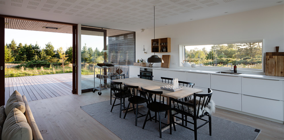 Medium sized scandinavian open plan dining room in Aarhus with white walls and light hardwood flooring.