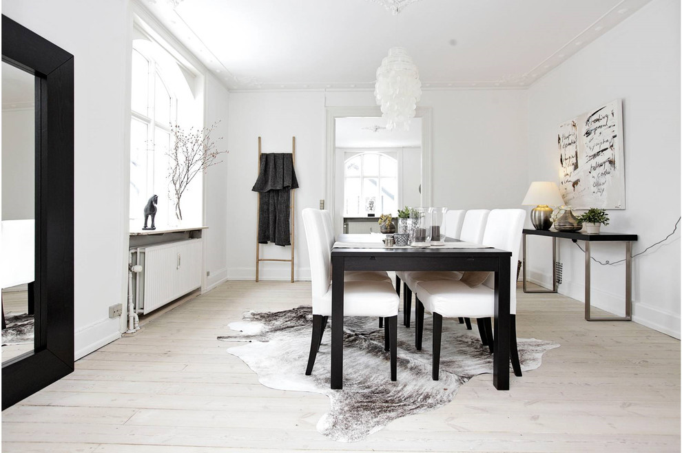 Medium sized scandinavian enclosed dining room in Copenhagen with white walls, light hardwood flooring and beige floors.