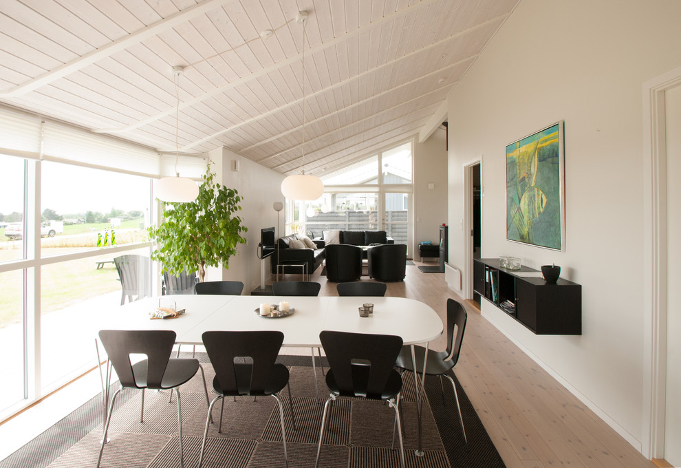 Immagine di una sala da pranzo aperta verso il soggiorno scandinava con pareti bianche e parquet chiaro