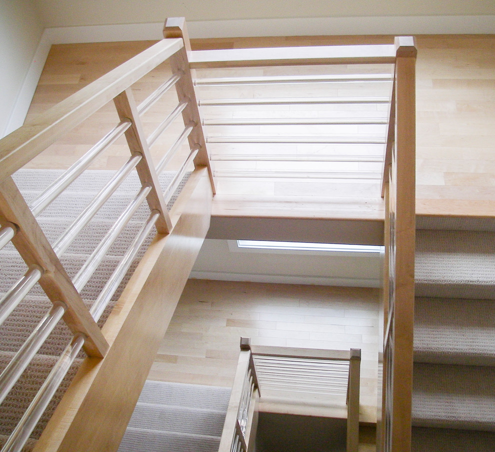 Cette image montre un escalier minimaliste en U de taille moyenne avec des marches en bois et un garde-corps en verre.