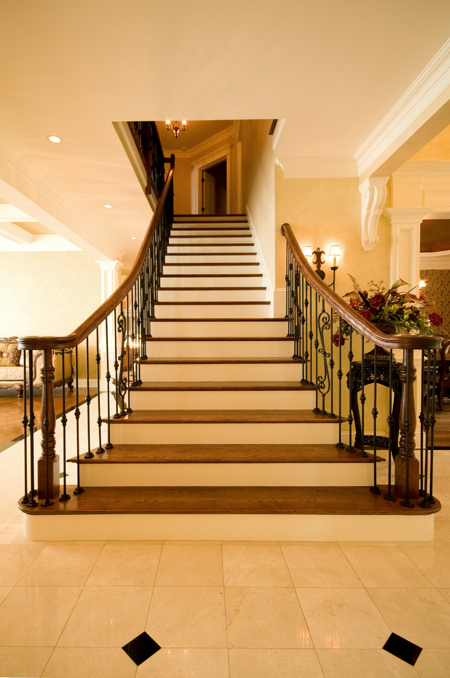 ボストンにあるラグジュアリーな広いトラディショナルスタイルのおしゃれな直階段 (フローリングの蹴込み板、木材の手すり) の写真