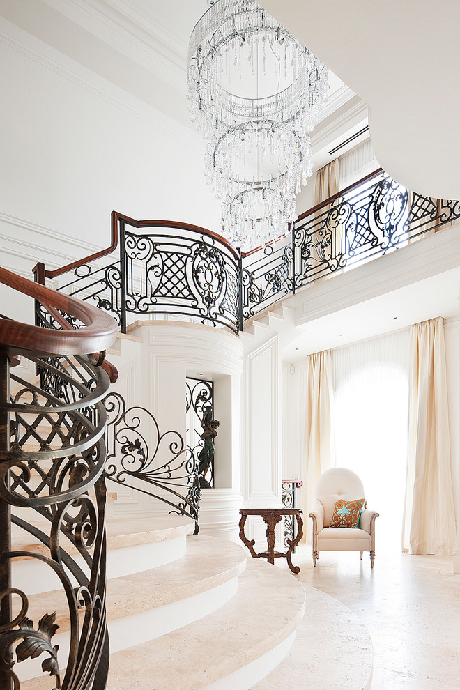Large elegant travertine curved staircase photo in Melbourne with painted risers