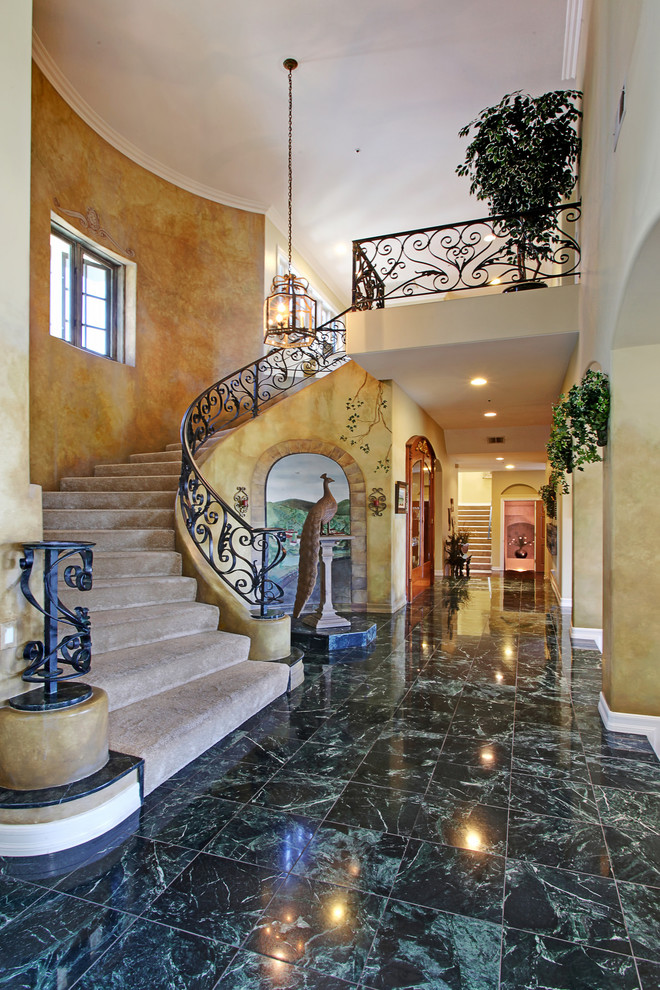 Источник вдохновения для домашнего уюта: изогнутая лестница в средиземноморском стиле с ступенями с ковровым покрытием и ковровыми подступенками