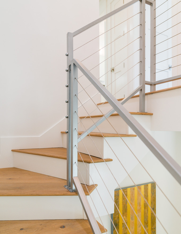 Идея дизайна: большая угловая лестница в стиле неоклассика (современная классика) с деревянными ступенями, крашенными деревянными подступенками и металлическими перилами