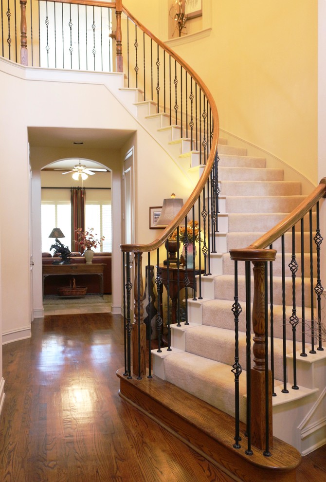 Пример оригинального дизайна: изогнутая лестница среднего размера в классическом стиле с ступенями с ковровым покрытием, крашенными деревянными подступенками и металлическими перилами