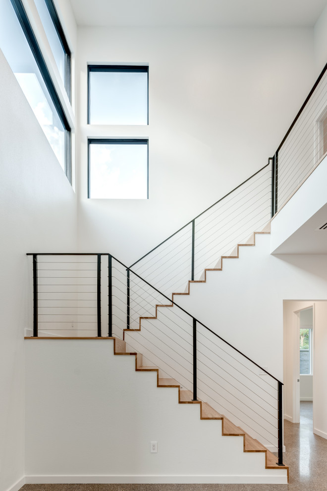 Modelo de escalera en U minimalista con escalones de madera, contrahuellas de madera y barandilla de cable