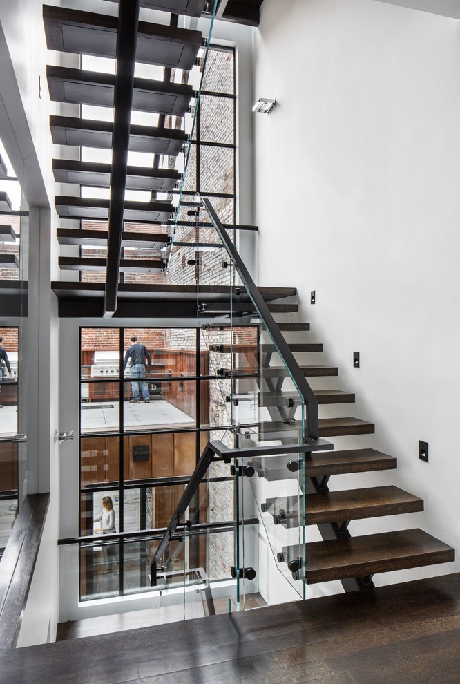 Bild på en funkis u-trappa i trä, med öppna sättsteg och räcke i glas