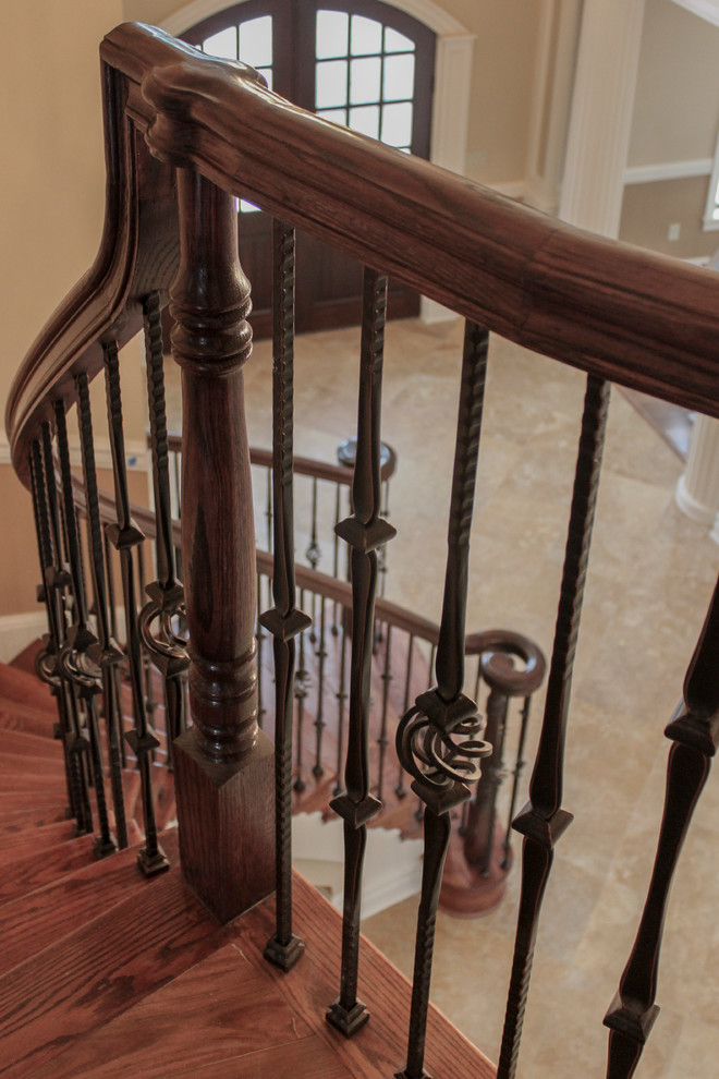 Idée de décoration pour un très grand escalier courbe tradition avec des marches en bois, des contremarches en bois et un garde-corps en matériaux mixtes.