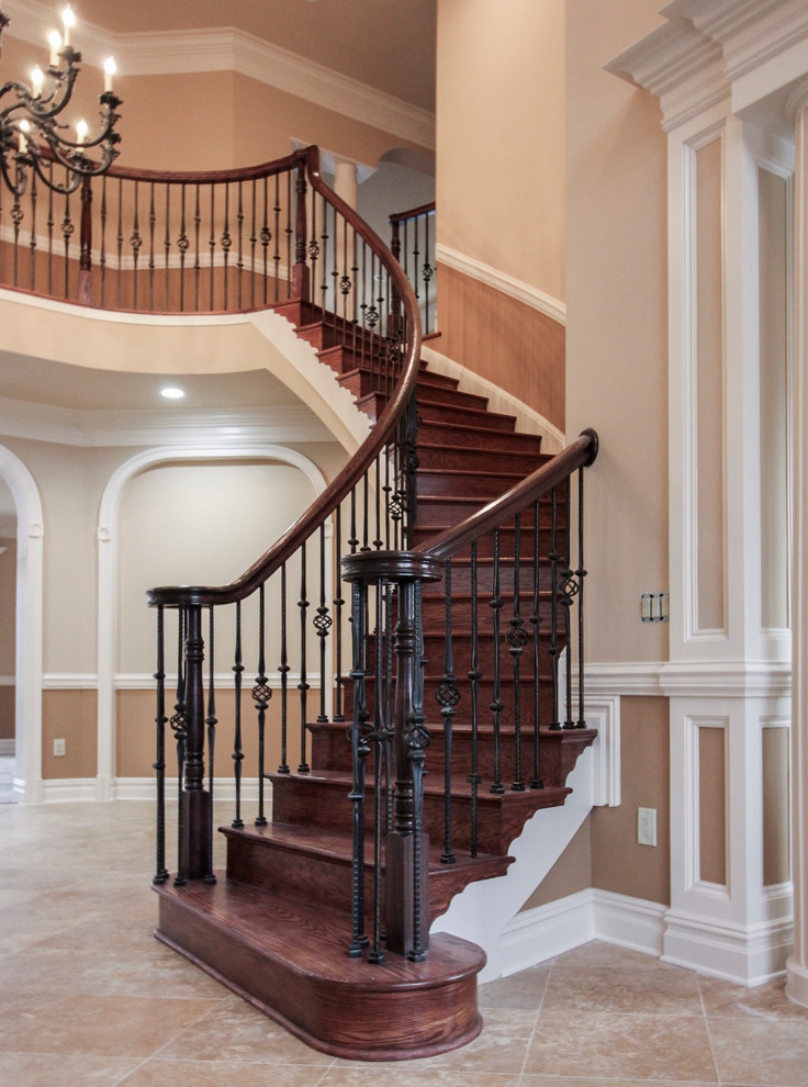 Идея дизайна: огромная изогнутая деревянная лестница в классическом стиле с деревянными ступенями и перилами из смешанных материалов