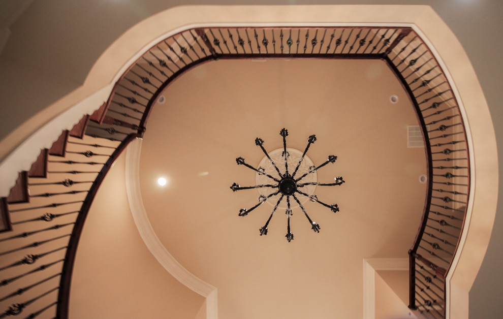 Imagen de escalera curva clásica extra grande con escalones de madera, contrahuellas de madera y barandilla de varios materiales