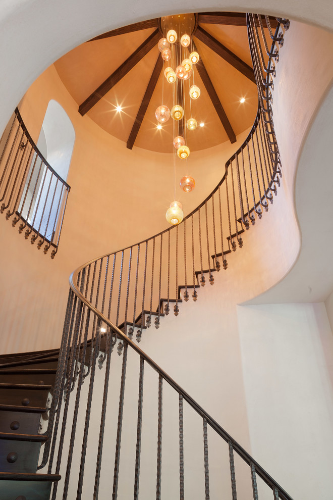 Example of a large tuscan wooden curved metal railing staircase design in Houston with wooden risers