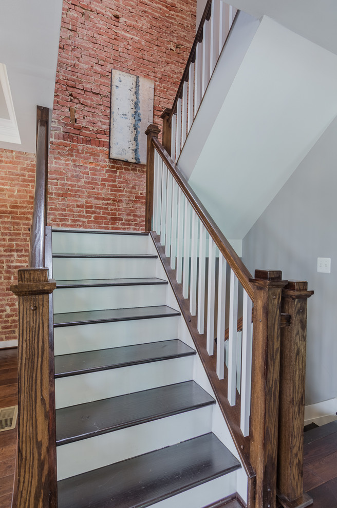 На фото: большая п-образная лестница в стиле лофт с деревянными ступенями и крашенными деревянными подступенками с