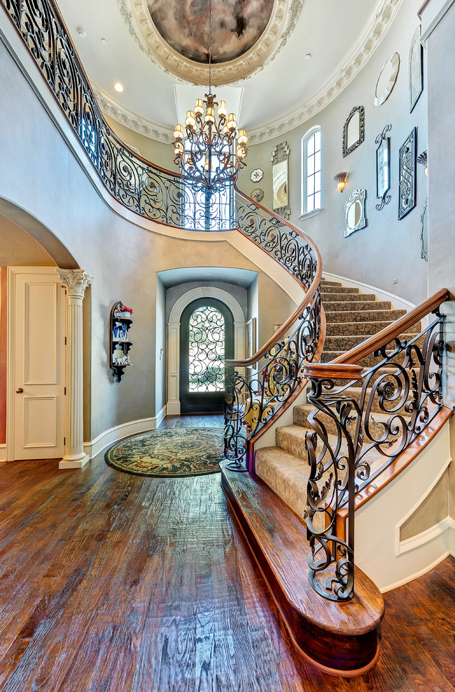 На фото: изогнутая лестница в классическом стиле с ступенями с ковровым покрытием и ковровыми подступенками