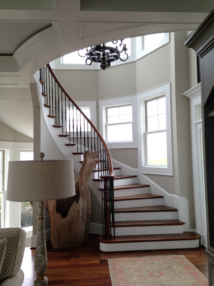 Large nautical wood curved staircase in Other with painted wood risers and feature lighting.