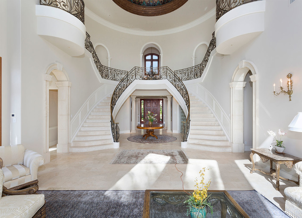 Aménagement d'un grand escalier courbe classique en marbre avec des contremarches en métal et un garde-corps en métal.