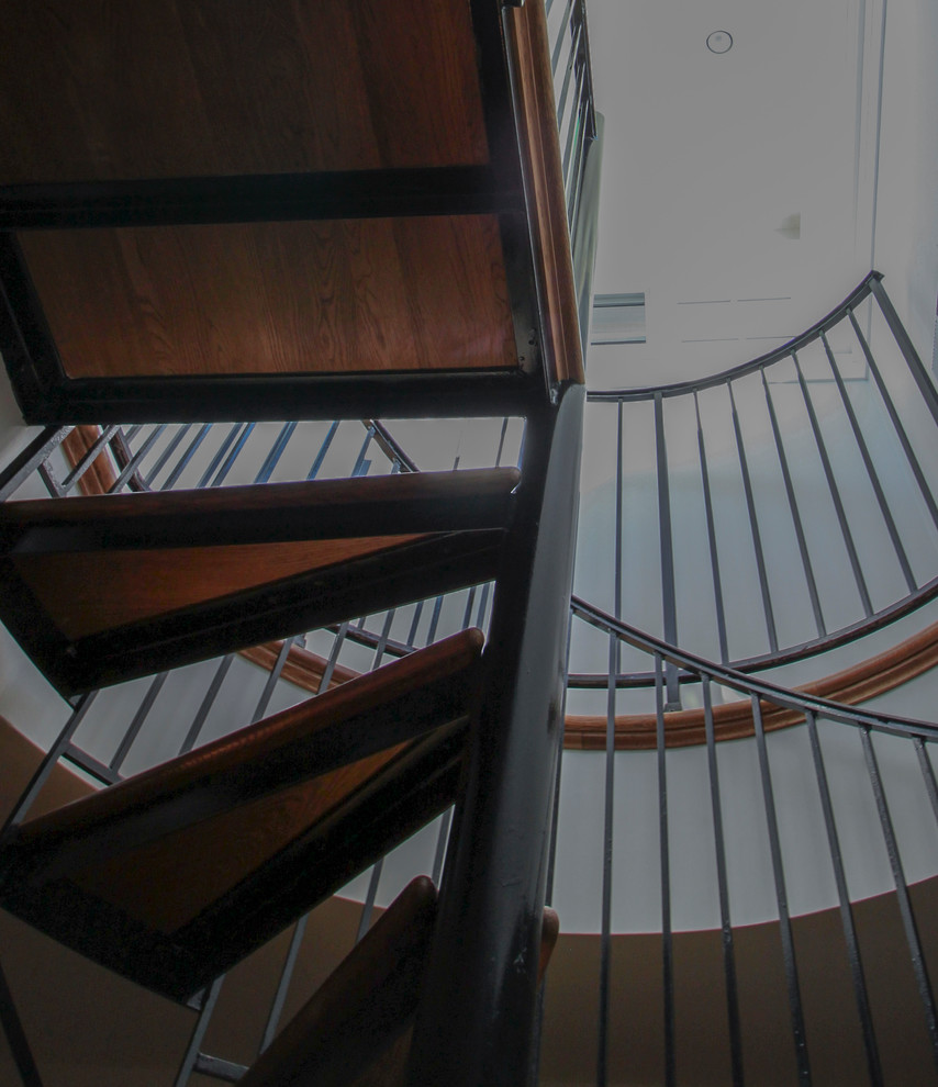 Aménagement d'un très grand escalier hélicoïdal classique avec des marches en bois, des contremarches en bois et un garde-corps en métal.