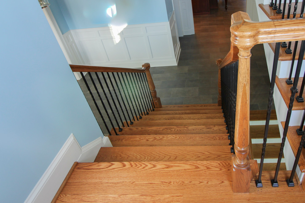 Esempio di un'ampia scala a chiocciola tradizionale con pedata in legno, alzata in legno e parapetto in metallo