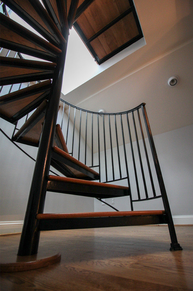 Cette photo montre un très grand escalier hélicoïdal chic avec des marches en bois, des contremarches en bois et un garde-corps en métal.