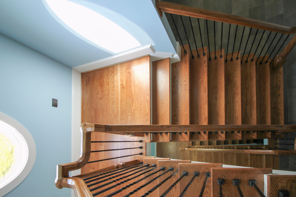 Пример оригинального дизайна: огромная винтовая деревянная лестница в классическом стиле с деревянными ступенями и металлическими перилами