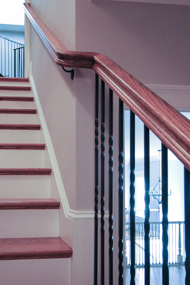 Ejemplo de escalera de caracol clásica extra grande con escalones de madera, contrahuellas de madera y barandilla de metal