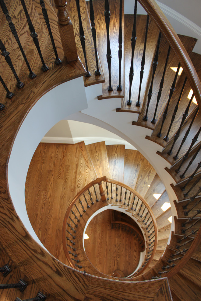 Ejemplo de escalera curva mediterránea grande con escalones de madera, contrahuellas de madera y barandilla de varios materiales