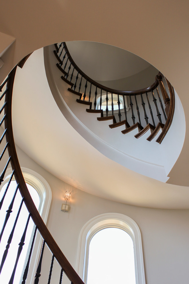 Photo of a large mediterranean wood curved mixed railing staircase in DC Metro with wood risers.