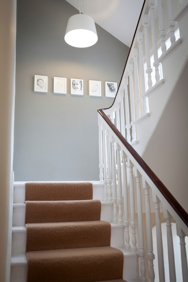 Идея дизайна: большая п-образная лестница в викторианском стиле с ступенями с ковровым покрытием и ковровыми подступенками