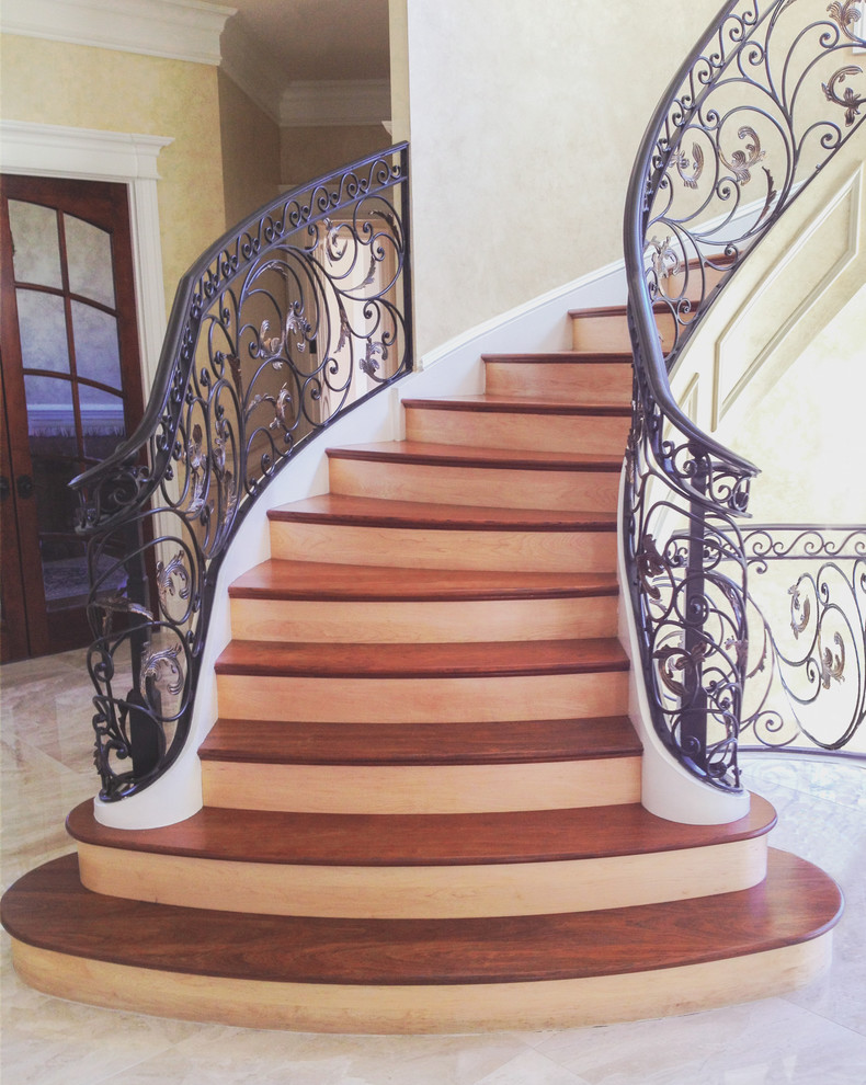 Idée de décoration pour un grand escalier courbe méditerranéen avec des marches en bois, des contremarches en bois et un garde-corps en matériaux mixtes.