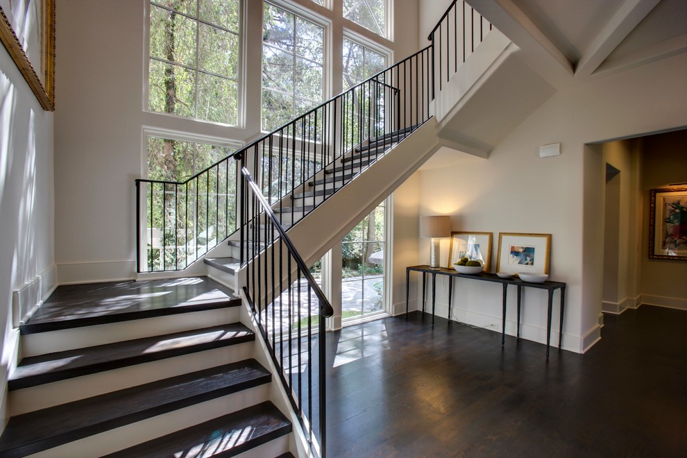 Photo of a large classic wood u-shaped metal railing staircase in Atlanta with painted wood risers and feature lighting.