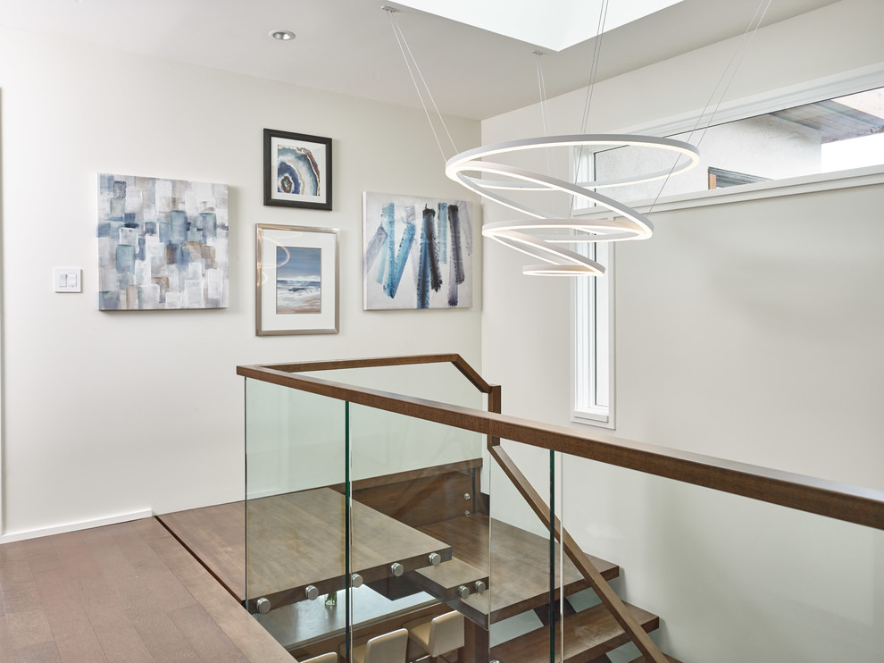 Idée de décoration pour un escalier sans contremarche design avec des marches en bois et un garde-corps en verre.