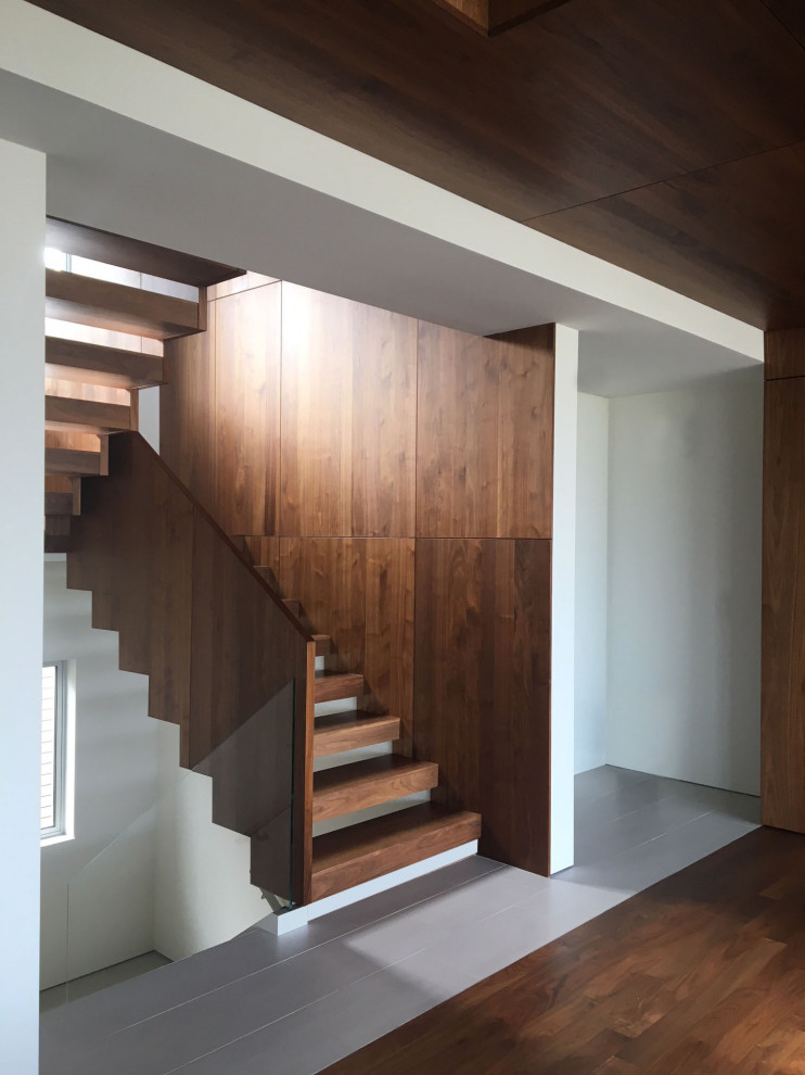 Ejemplo de escalera en L minimalista con escalones de madera, contrahuellas de madera y barandilla de madera