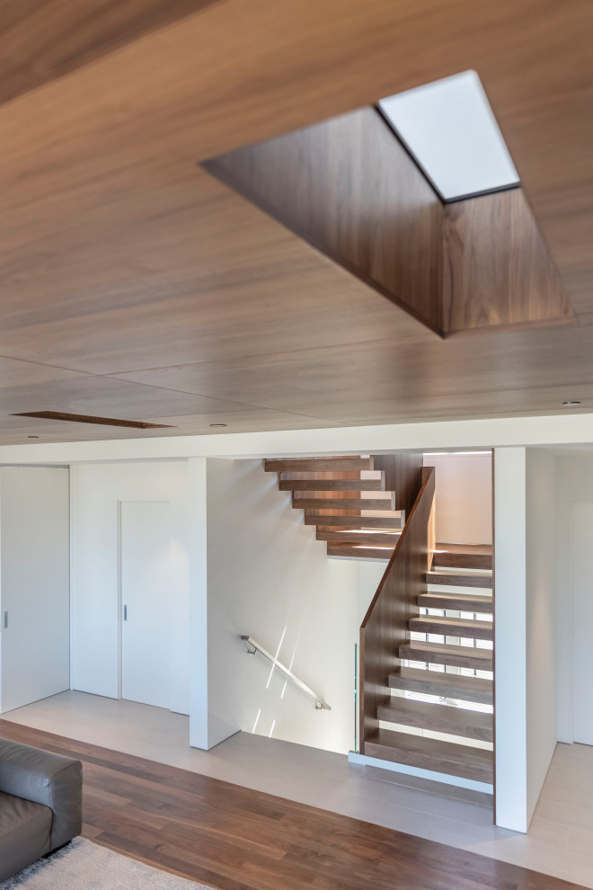 Idée de décoration pour un escalier minimaliste en L avec des marches en bois, des contremarches en bois et un garde-corps en bois.