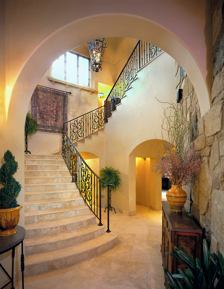 На фото: п-образная лестница в средиземноморском стиле с ступенями из травертина, подступенками из травертина и металлическими перилами