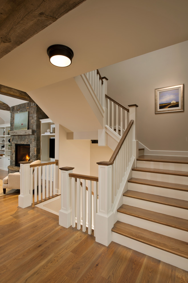 This is an example of a traditional wood curved staircase in New York with wood risers and feature lighting.