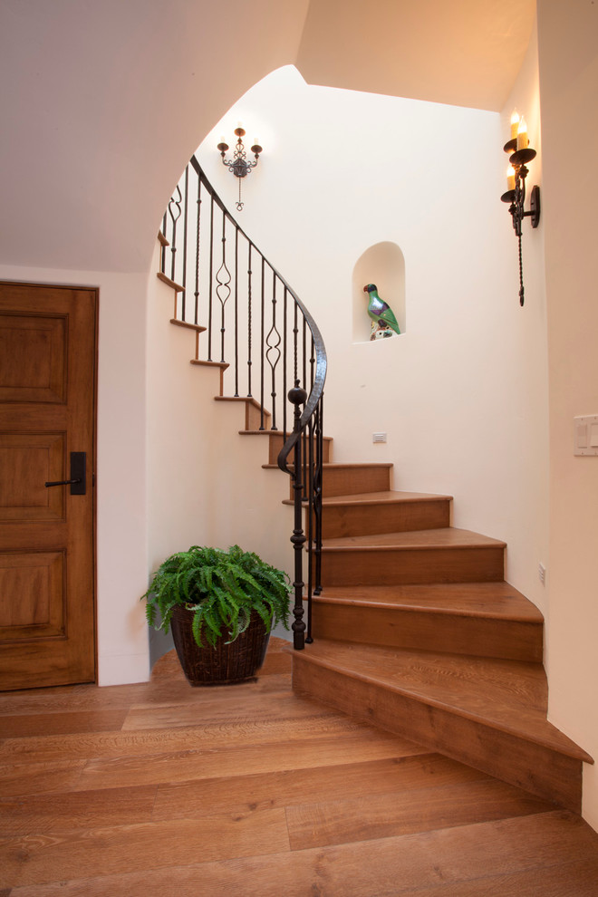Photo of a medium sized mediterranean wood curved staircase in San Diego with wood risers.