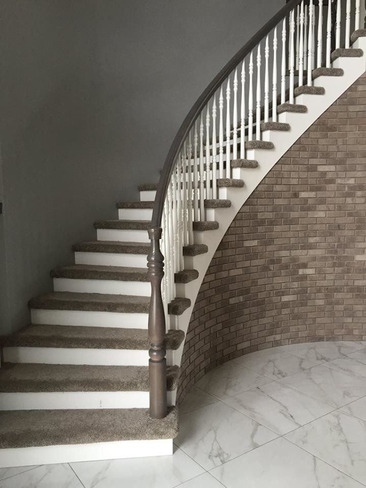 Exempel på en klassisk svängd trappa, med heltäckningsmatta och sättsteg i målat trä