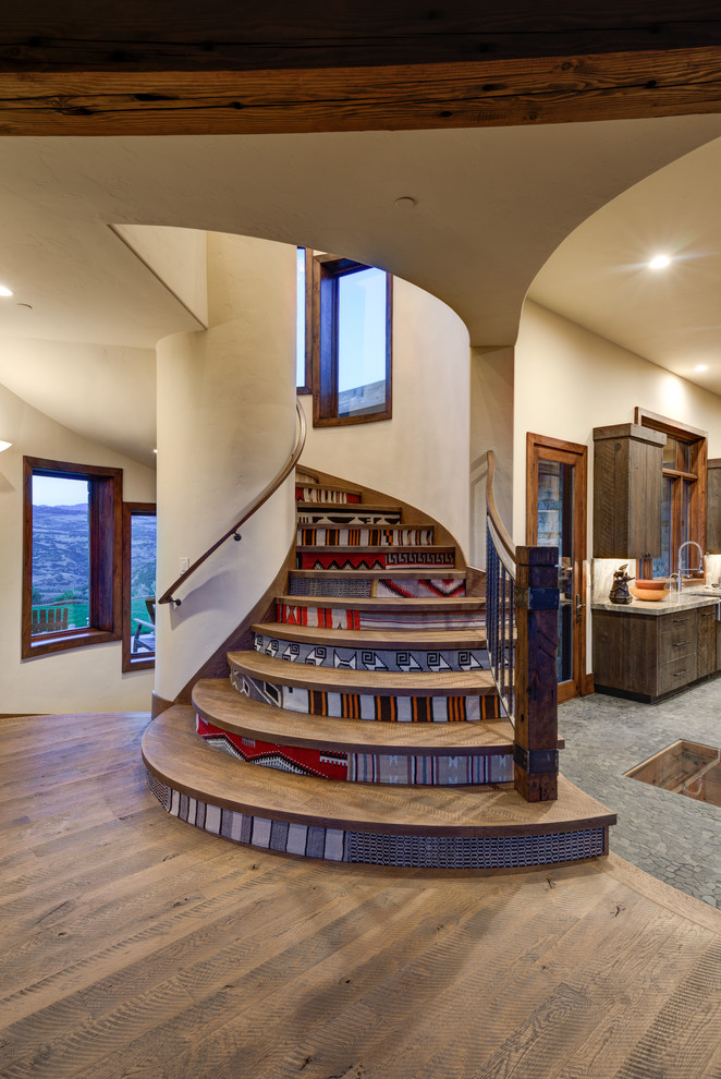 Imagen de escalera curva rural de tamaño medio con escalones de madera, contrahuellas con baldosas y/o azulejos y barandilla de varios materiales