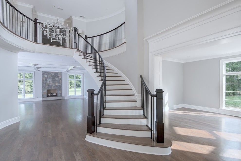Imagen de escalera curva contemporánea grande con escalones de madera, contrahuellas de madera pintada y barandilla de varios materiales