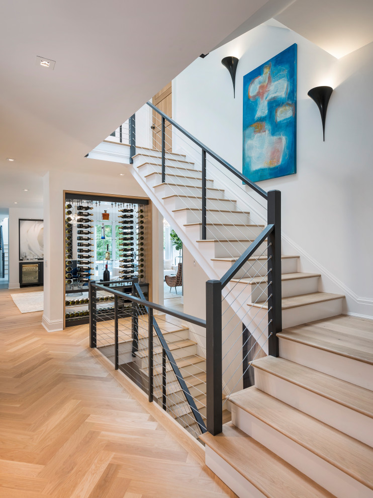 Свежая идея для дизайна: большая угловая лестница в стиле неоклассика (современная классика) с деревянными ступенями и металлическими перилами - отличное фото интерьера