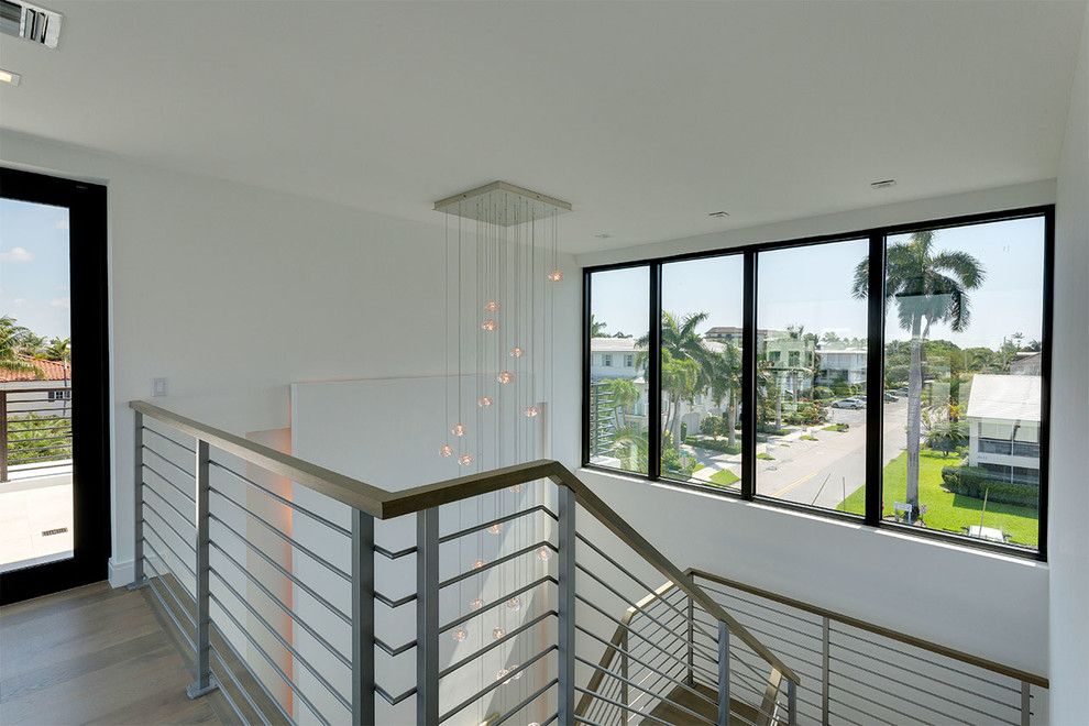 This is an example of a medium sized contemporary wood u-shaped metal railing staircase in Miami with metal risers.