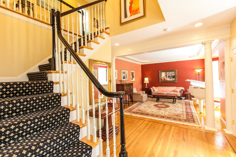 This is an example of a large classic carpeted l-shaped wood railing staircase in Boston with carpeted risers and feature lighting.